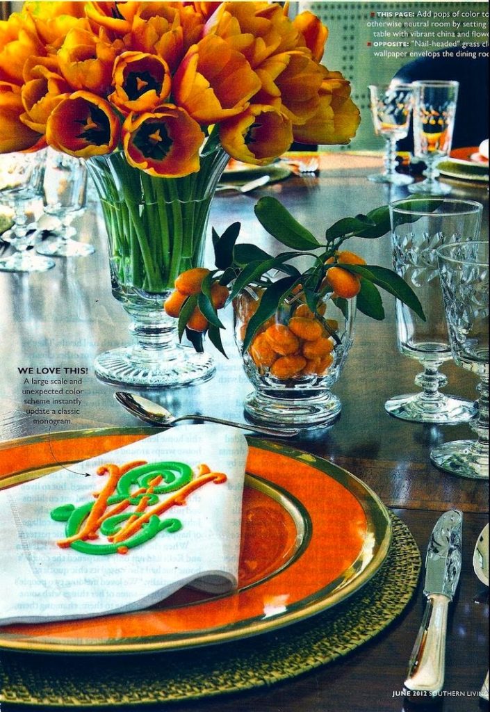 Festive dining room table setting with orange charger, monogrammed napkins and kumquat centerpiece.